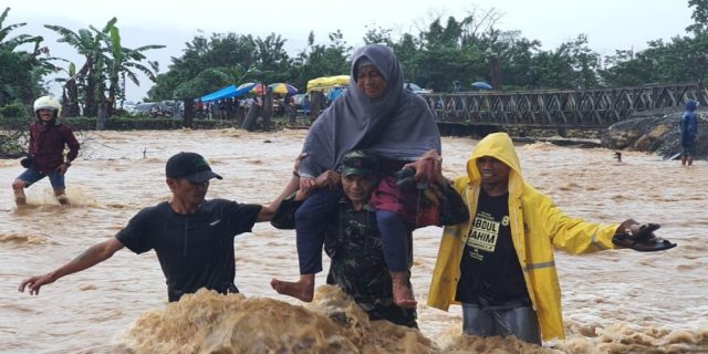 TNI Koramil 1311-02/Bahodopi Panggul Warga Seberangi Jalan Akibat Luapan Air Sungai